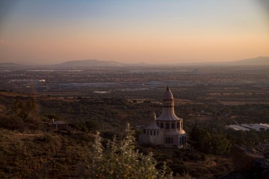 Stunning aerial view of the Santuario de los Martires with a picturesque Mexican landscape at sunset.