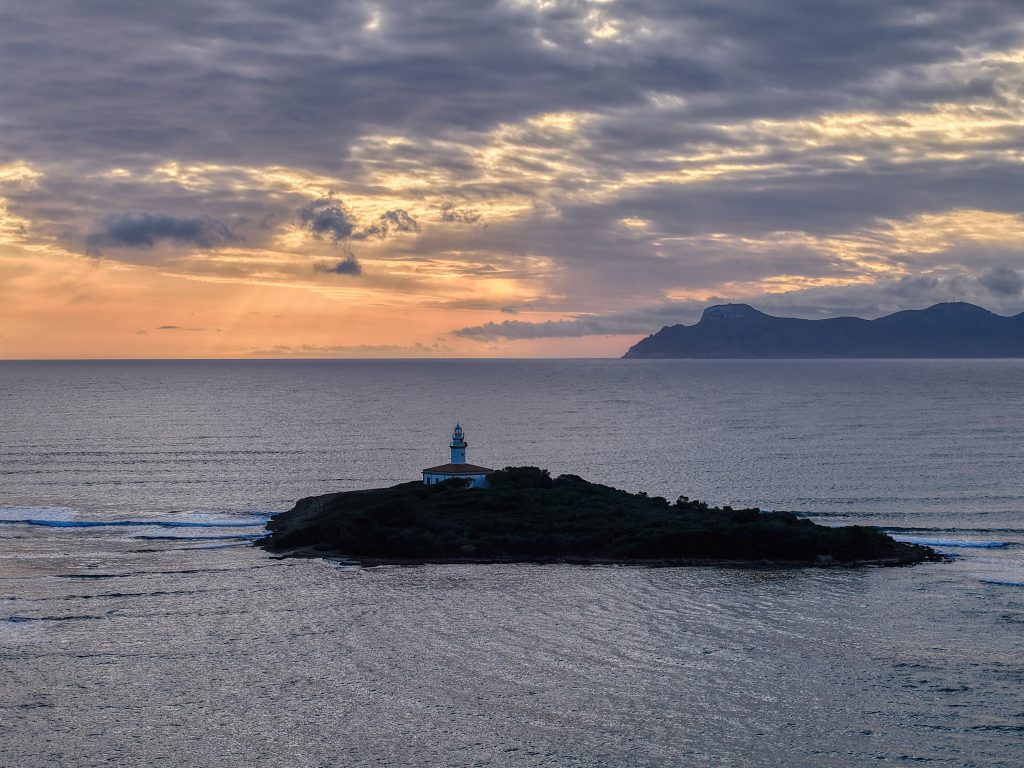 Breathtaking sunset over Sa Dragonera Island in Mallorca, featuring a lone lighthouse against a dramatic sky.